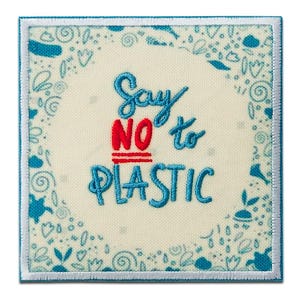 Könnte beinhalten: Ein quadratischer Stickaufnäher mit cremefarbenem Stoffuntergrund. Der Text "Say NO to PLASTIC" ist mit blauem und rotem Garn gestickt. Eine Umrandung aus blauen, gestickten botanischen und abstrakten Formen rahmt den Text auf dem Aufnäher ein.