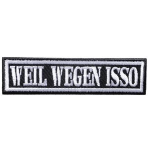 Op de afbeelding: Zwart rechthoekig embleem met witte geborduurde tekst "WEIL WEGEN ISSO". De patch heeft een witte rand en is ontworpen om op kleding of accessoires te worden genaaid of gestreken.