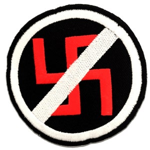 Puede incluir: Parche redondo negro con borde blanco y una franja diagonal blanca que cruza una esvástica roja. El parche está bordado.
