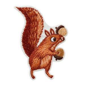 May include: Embroidered patch of a brown squirrel holding two acorns. The squirrel has a bushy tail and large, round eyes.