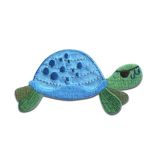 Könnte beinhalten: Blau-grüner gestickter Bügelaufkleber mit einer Cartoon-Schildkröte mit Augenklappe.