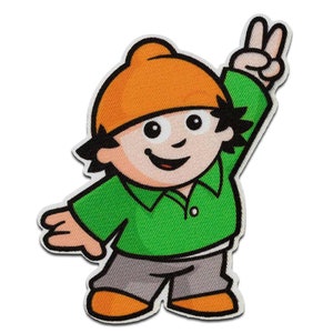 Könnte beinhalten: Eine Comicfigur mit orangefarbenem Haar und einem grünen Hemd zeigt ein Peace-Zeichen. Die Figur trägt eine graue Mütze und eine graue Hose.