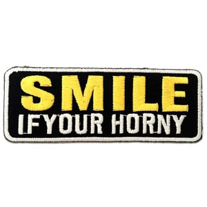 Könnte beinhalten: Schwarzer gestickter Aufnäher mit weißen Nähten. Der Aufnäher sagt "SMILE IF YOUR HORNY" in gelben Buchstaben.
