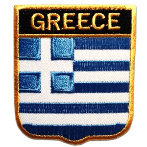 May include: Embroidered patch depicting the Greek flag. The patch has a black top border with the word "GREECE" in gold lettering. The flag design features blue and white stripes and a white cross in the upper left corner, with a gold border.
