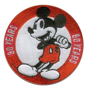 Könnte beinhalten: Ein gestickter Aufnäher mit Mickey Mouse in einer klassischen Pose. Der Aufnäher ist rund und hat den Text "90 YEARS" auf der linken Seite und "90 YEARS" auf der rechten Seite.