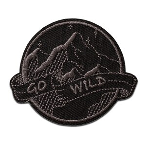Könnte beinhalten: Schwarzer gestickter Aufnäher mit einem Bergketten-Design und dem Text "Go Wild" in einem Banner.