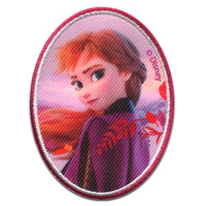 Può includere: Un cerotto ovale in tessuto rosa con un bordo bianco. Il cerotto presenta un'immagine colorata di una giovane donna con lunghi capelli rossi, che indossa un vestito viola. Il testo "© Disney" è visibile nell'angolo in alto a destra del cerotto.