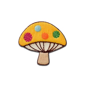 Può includere: Una toppa ricamata a forma di fungo con un cappello giallo caratterizzato da quattro pois circolari nei colori azzurro, rosa, arancione e verde. La parte inferiore del cappello presenta lamelle bianche con cuciture marroni e il gambo è beige.