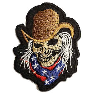 Op de afbeelding: Geborduurde patch met een schedel met een cowboyhoed en een bandana. De hoed is bruin, de bandana is blauw met witte sterren en rode strepen. De schedel heeft wit haar en staat tegen een zwarte achtergrond.