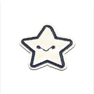 Op de afbeelding: Een witte, stervormige patch met een marineblauwe geborduurde omtrek en een lachend gezicht. De patch heeft een getextureerd uiterlijk en is waarschijnlijk gemaakt van stof. Het ontwerp is eenvoudig en vrolijk, geschikt voor kleding of accessoires.