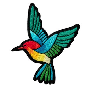 Può includere: Toppa ricamata di un colibrì in volo. L'uccello presenta colori vivaci, tra cui rosso, blu, giallo e verde, con un contorno nero. Le ali sono spiegate, mostrando cuciture dettagliate.