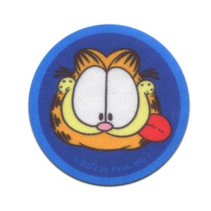 Pode incluir: Um remendo redondo azul com uma borda branca apresentando uma imagem de desenho animado de Garfield o gato com pelo laranja, listras pretas e uma língua vermelha para fora.