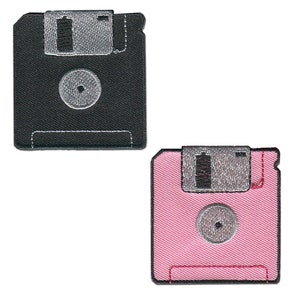 Może przedstawiać: Dwa naszywki w kształcie dyskietki do prasowania. Jedna jest czarna z srebrną etykietą, a druga jest różowa z srebrną etykietą.