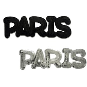Op de afbeelding: Twee strijkbare patches met het woord "PARIS" in een vetgedrukt, bubbelvormig lettertype. De bovenste patch is zwart en de onderste patch is zilver met pailletten.