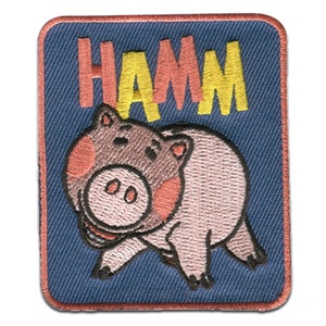 Könnte beinhalten: Gestickter Aufnäher mit einem Cartoon-Schwein mit rosa Wangen und dem Wort "HAMM" in gelben und roten Buchstaben auf blauem Hintergrund.