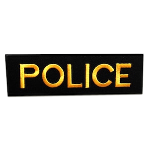 Könnte beinhalten: Schwarzer Stoff-Patch mit dem Wort "POLICE" in gelber Stickerei.