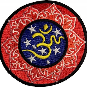 Pode incluir: Patch bordado com um design circular. O patch apresenta uma borda externa vermelha com um padrão floral, uma borda preta e um centro azul. O centro contém um símbolo Om amarelo e estrelas brancas.