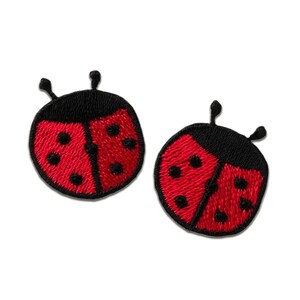 Peut inclure: Deux écussons brodés représentant des coccinelles. Chaque écusson présente un corps rouge avec des points noirs et une tête noire avec des antennes. Les écussons sont conçus pour être cousus ou repassés sur du tissu, adaptés aux vêtements ou aux accessoires.