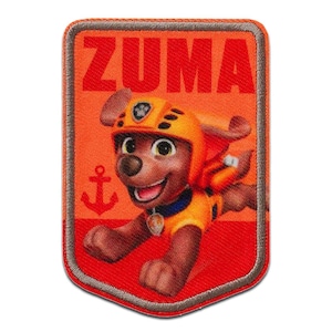 Op de afbeelding: Rechthoekige patch met Zuma van Paw Patrol. De patch heeft een rode en oranje achtergrond met het woord "ZUMA" bovenaan. Zuma, een bruine hond, draagt een oranje helm en uniform. Aan de linkerkant staat een anker.