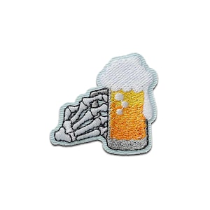 Könnte beinhalten: Gestickter Aufnäher mit einer Skeletthand, die einen Bierkrug hält. Das Bier ist goldfarben mit weißem Schaum, und die Hand ist weiß vor einem hellblauen Rand. Ein lustiges Design für Kleidung oder Accessoires.