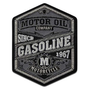 May include: A black and grey embroidered patch featuring the text "MOTOR OIL COMPANY" and "GASOLINE 1967." The patch is hexagonal, with a decorative border and the word "MOTORCYCLE" at the bottom.