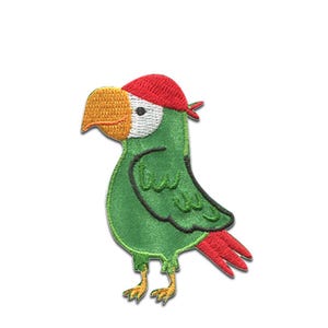 Könnte beinhalten: Gestickter Aufnäher eines Cartoon-Papageis in Grün, Rot und Gelb. Der Papagei trägt ein rotes Bandana und hat einen gelben Schnabel. Der Aufnäher ist für das Aufnähen auf Kleidung oder Accessoires konzipiert.