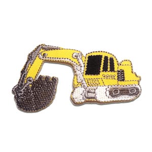 Könnte beinhalten: Gestickter Aufnäher eines gelben Baggers mit schwarzer Kabine und braunem Eimer. Der Aufnäher hat einen weißen Rand und ist zum Aufbügeln bestimmt. Der Bagger ist ein Cartoon-Design.