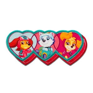 Op de afbeelding: Geborduurde patch met drie stripfiguren uit de Paw Patrol-serie, elk in een hartvormige lijst. De karakters zijn in levendige kleuren, met een rood, roze en blauwgroen kleurenschema. De patch heeft een blauwgroene rand en een rode hartomtrek.