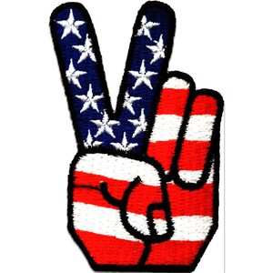 Könnte beinhalten: Gestickter Aufnäher in Form einer Hand, die das Friedenszeichen zeigt. Die Finger sind mit dem Design der amerikanischen Flagge gefärbt: blau mit weißen Sternen und rot-weißen Streifen.