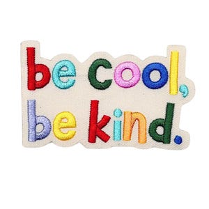 May include: Embroidered patch with the words "be cool, be kind" in colorful thread. The patch has a cream-colored background and a wavy border. The text is in a variety of colors, including red, blue, green, and yellow.