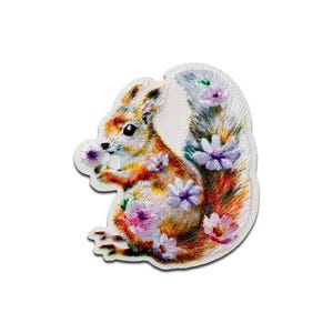 May include: Embroidered patch of a squirrel holding a purple flower. The squirrel has orange, brown, and white fur, with a fluffy tail decorated with purple and pink flowers. The patch is on a white background.