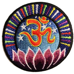 Op de afbeelding: Gestikt patch met een kleurrijk om-symbool omringd door een blauwe cirkel met witte sterren en een lotusbloem aan de onderkant. Het om-symbool is rood en geel en de lotusbloem is paars.