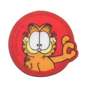 Könnte beinhalten: Ein roter runder Patch mit einem Cartoon-Bild von Garfield der Katze, der einen Daumen hoch zeigt. Der Text "© 1978 Paws, Inc." ist im Hintergrund sichtbar.