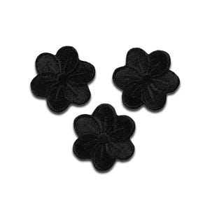 May include: Three black embroidered flower patches. Each patch has a six-petal design with detailed stitching. The patches are arranged on a white background, showcasing their intricate floral pattern. Suitable for fabric embellishment.