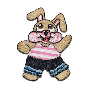 May include: A brown bunny wearing a pink and white striped shirt and blue jeans. The bunny has pink cheeks and a big smile.
