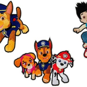 Op de afbeelding: Vier geborduurde strijkpatches met personages uit de kinderserie Paw Patrol. De patches bevatten Chase, de politiehond, Skye, de roze pup, Marshall, de brandweerhond, en Ryder, het menselijke personage.