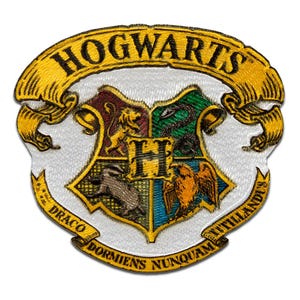 Op de afbeelding: Geborduurde patch met het Hogwarts-wapen. Het wapen is een schild verdeeld in vier secties, die elk een Hogwarts-huis vertegenwoordigen. De patch bevat de woorden "Hogwarts" en de spreuk "Draco Dormiens Nunquam Titillandus".