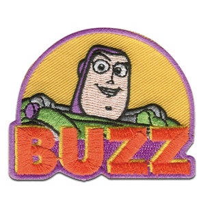 Può includere: Toppa ricamata viola e arancione con un'immagine di cartone animato di Buzz Lightyear del franchise Toy Story. La toppa presenta il testo "BUZZ" in grandi caratteri grassetto.