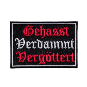 Op de afbeelding: Zwarte rechthoekige patch met witte rand. De patch bevat de Duitse woorden "Gehasst", "Verdammt" en "Vergöttert" in rode en witte gotische letters.