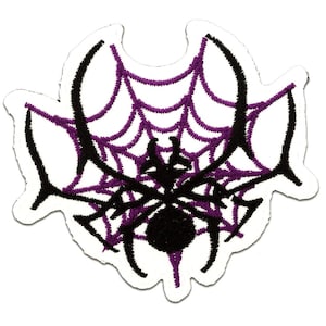 Könnte beinhalten: Gestickter Aufnäher mit einer schwarzen Spinne auf einem lila Spinnennetz. Die Spinne hat einen runden Körper und lange Beine. Das Netz ist ein detailliertes Design mit geschwungenen Linien. Der Aufnäher hat einen weißen Rand.