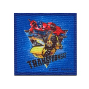 Può includere: Una toppa quadrata blu con personaggi di Transformers. Il design include Optimus Prime in rosso, Bumblebee in giallo e la scritta "TRANSFORMERS" in nero. La toppa ha un bordo blu e uno sfondo bianco.