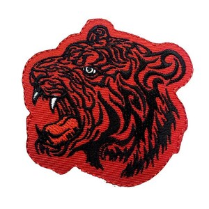 Könnte beinhalten: Roter gestickter Aufnäher mit einer schwarzen Umrandung eines brüllenden Tigerkopfes.