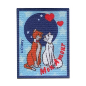 May include: A blue and white fabric patch with a red heart and the text "MONA" in red. The patch features two cartoon cats, one orange and one white, looking at each other. The text "© Disney" is in the upper left corner.