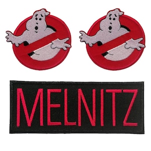 Op de afbeelding: Twee ronde geborduurde patches met een wit spookfiguur in een rode cirkel met een rode diagonale streep, en één rechthoekige zwarte patch met de naam MELNITZ geborduurd in opvallende roze hoofdletters.
