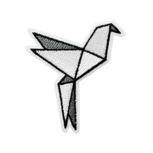 Può includere: Toppa ricamata con un design geometrico di uccello origami. La toppa è principalmente bianca con accenti neri, che presenta un'estetica moderna e minimalista. L'uccello è raffigurato in volo, con cuciture dettagliate che ne delineano la forma.