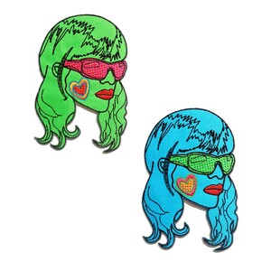 Peut inclure: Deux patchs brodés thermocollants représentant une femme de dessin animé stylisée aux cheveux longs, portant des lunettes de soleil et un fard à joues en forme de cœur. Un patch est vert et l'autre est bleu.