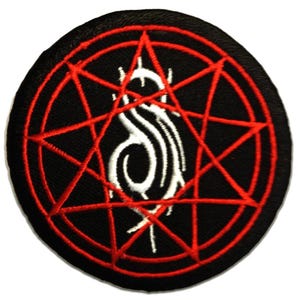May include: A circular black patch with a red pentagram design and a white stylized symbol at the centre. This patch is likely for clothing or accessories, and is a symbol of a heavy metal band.