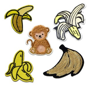 Könnte beinhalten: Fünf Bügelbilder mit einem Affen, einer Banane und drei verschiedenen Bananenstilen. Der Affe ist braun und hat eine flauschige Textur. Die Bananen sind gelb und haben verschiedene Texturen, darunter Pailletten und Stickereien.