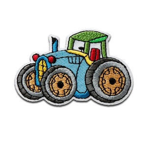 Może przedstawiać: Haftowana naszywka przedstawiająca traktor z kreskówki. Traktor jest głównie jasnoniebieski z zielonym dachem, żółtymi akcentami i czerwonymi światłami. Koła są szare z brązowymi środkami, a naszywka ma białą obwódkę.