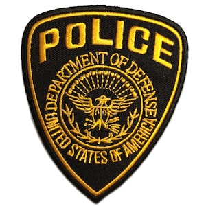 Peut inclure: Un écusson brodé noir et or avec le mot "POLICE" en grandes lettres et les mots "Department of Defense United States of America" en cercle autour d'un aigle stylisé.